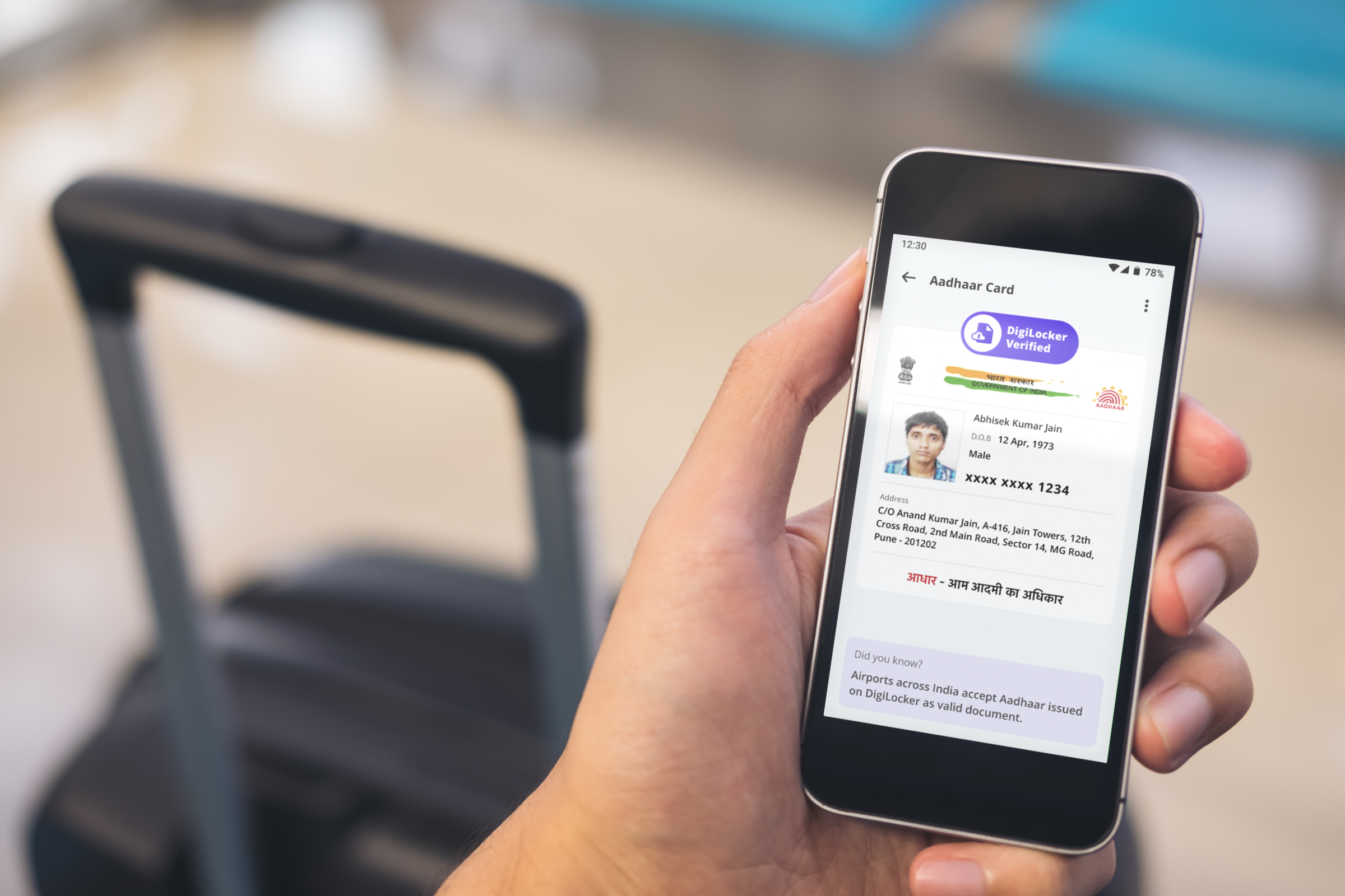 Hand holding phone with Digilocker screen. Suitcase with handle in background